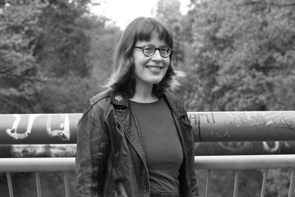 Zu sehen ist ein Foto der Autorin Koschka Linkerhand in Schwarz-weiß. Sie trägt eine Lederjacke und eine Brille
